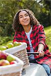 Beautiful happy mixed race African American girl teenager female young woman smiling with perfect teeth in an orchard driving a tractor with baskets of organic apples she has been picking