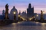 Street lanterns and old statues frame the historical buildings on Charles Bridge at dawn, UNESCO World Heritage Site, Prague, Czech Republic, Europe