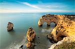 Sunrise on cliffs framed by turquoise water of the ocean, Praia da Marinha, Caramujeira, Lagoa Municipality, Algarve, Portugal, Europe