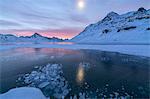 Ice bubbles frame the frozen Lago Bianco at dawn, Bernina Pass, canton of Graubunden, Engadine, Switzerland, Europe