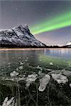 Ice bubbles of frozen sea and the snowy peak of Otertinden under the Northern Lights (aurora borealis), Oteren, Lyngen Alps, Troms, Norway, Scandinavia, Europe