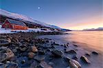 Fiery sky at sunset and typical Rorbu, snowy peaks and frozen sea, Djupvik, Lyngen Alps, Troms, Norway, Scandinavia, Europe