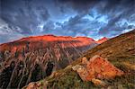 Dark clouds and sunset light frame the rocky peaks of Muottas Muragl, St. Moritz, Canton of Graubunden, Engadine, Switzerland, Europe