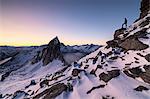 Hiker on peak Hesten admires Mount Segla and the Mefjorden framed by frozen sea at sunrise, Senja, Troms, Norway, Scandinavia, Europe