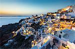 Sunset over the white stone buildings and windmills of Oia on the tip of Santorini's caldera, Santorini, Cyclades, Greek Islands, Greece, Europe