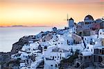 Sunset view over the whitewashed buildings and windmills of Oia from the castle walls, Santorini, Cyclades, Greek Islands, Greece, Europe