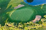 Aerial view of a golf course with lush green lawn, trees and bunkers.