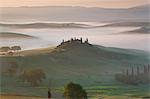 Sunrise across a misty Italian landscape of rolling hills and cypress trees, farmhouse in the distance.