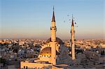 Cityscape at sunset, with mosque and minarets in the foreground.