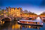 Canal scene with tour boat at dusk, Amsterdam, Netherlands, Europe