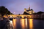 Notre Dame Cathedral and lights reflecting in the River Seine on a wet evening in Paris, France, Europe