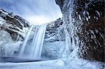 Winter view of Skogafoss waterfall, with cliffs covered in icicles and foregreound covered in snow, Skogar, South Iceland, Polar Regions