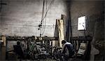 Mechanic sitting on armchair in workshop with dismantled vintage motorcycle