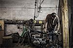 Mechanic inspecting dismantled vintage motorcycle in workshop