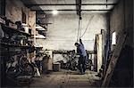 Mechanic hoisting dismantled vintage motorcycle in workshop