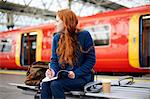 Woman on bench on train station platform, London