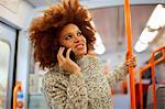 Woman using mobile phone on train, London