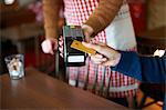Customer in cafe making contactless payment with credit card