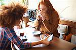 Friends with smartphone relaxing in cafe