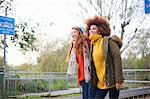 Friends on railway station looking away smiling