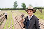 Portrait of farmer in field with hoe