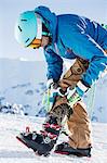 Mature man wearing skiwear, putting on ski boots