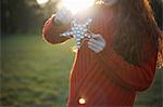Young woman in rural setting, holding Christmas star, mid section