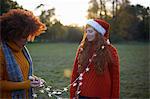 Two young women, in rural setting, young woman wrapped in fairy lights