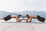 Two young men doing push ups on waterfront, Lake Como, Lombardy, Italy
