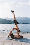 Two young men doing team handstand on waterfront, Lake Como, Lombardy, Italy