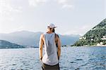 Rear view of young male hipster looking out from waterfront, Lake Como, Lombardy, Italy
