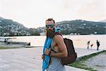 Portrait of young male hipster with backpack at lake Como, Lombardy, Italy