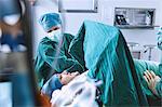 Surgeons preparing patient for surgery in maternity ward operating theatre