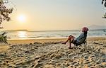 Woman on beach in deckchair looking away at sea, Florianopolis, Santa Catarina, Brazil, South America