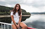 Woman sitting on safety barrier by lake, Koralat, Zagrebacka, Croatia