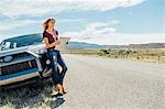 Woman with map leaning against car