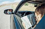 View over shoulder of woman sitting in car looking at map