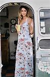 Portrait of young woman wearing maxi dress with fruit juice in airstream doorway