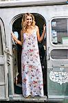 Young woman in maxi dress looking out from airstream doorway