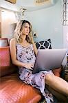 Young woman in airstream trailer using laptop