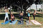 Girls and teenage schoolgirls practicing yoga warrior pose on school playing field