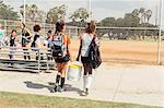 Girls and teenage schoolgirls carrying drinks cooler on school sports field