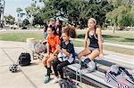 Male teacher and schoolgirls watching soccer practice on school sports field