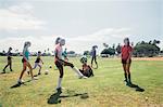 Schoolgirls practicing keepy uppy with soccer ball on school sports field