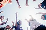 Low angle view of schoolgirl soccer team in circle with arms raised