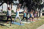 Schoolgirls practicing yoga warrior one pose on school sports field