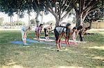 Schoolgirls practicing yoga pose on school sports field