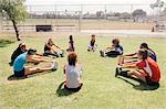 Schoolgirl soccer players warming up in circle on school sports field