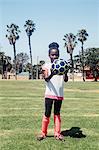 Portrait of schoolgirl soccer player holding soccer ball on school sports field