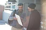 Two men in street, looking at map